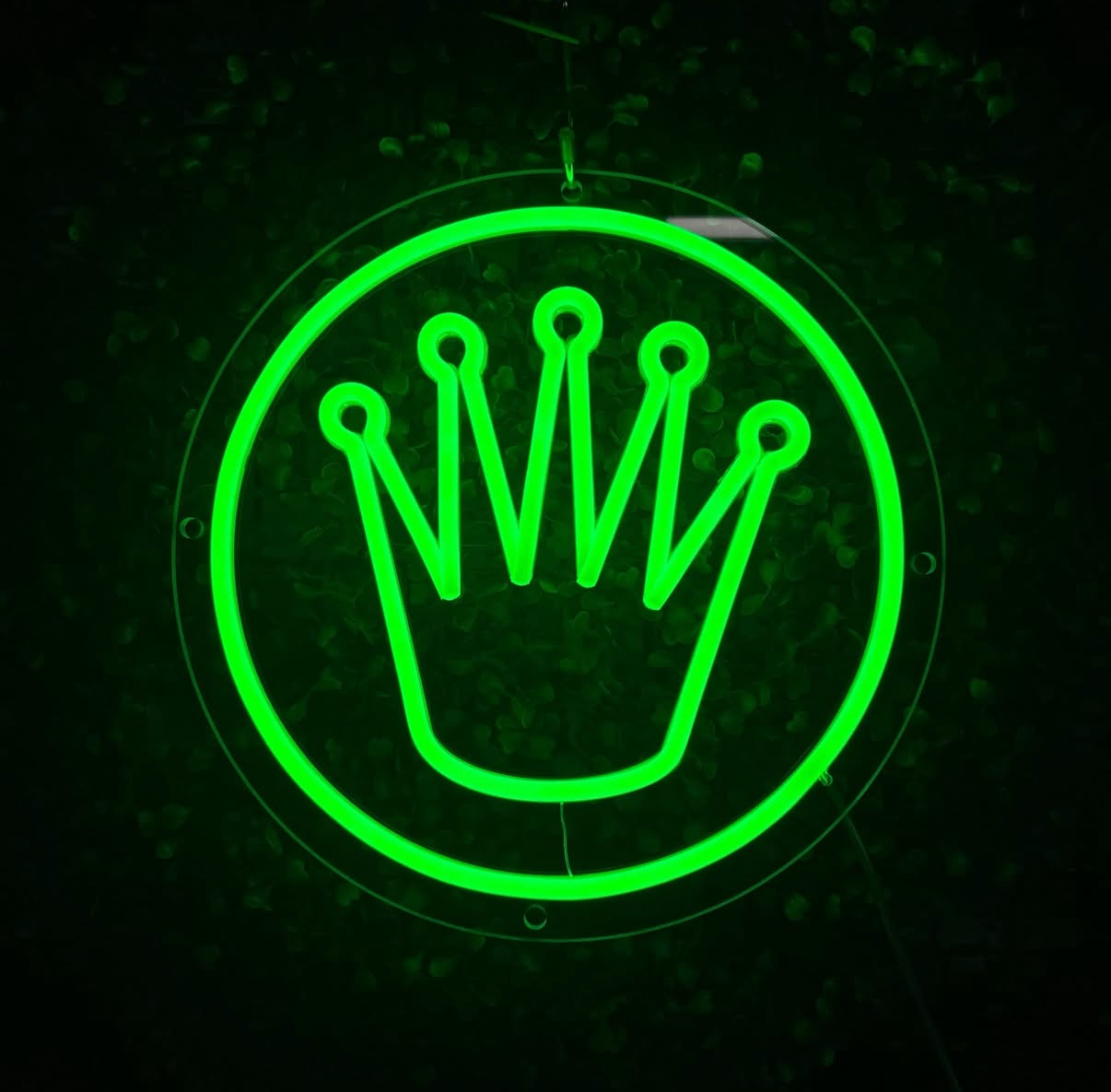 Glowing LED green rolex crown logo light on a dark background